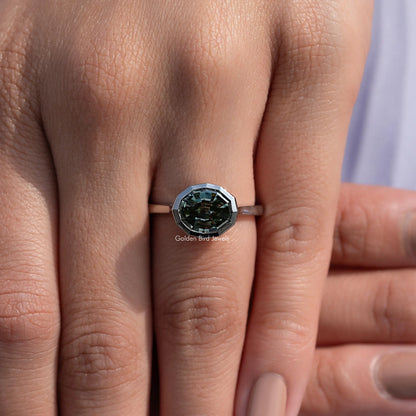 Bezel-set solitaire ring with dark green step-cut gemstone in an octagonal bezel