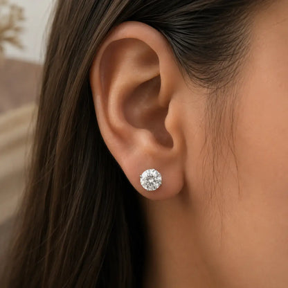 Round moissanite solitaire stud earring on ear with prong-set round stone.