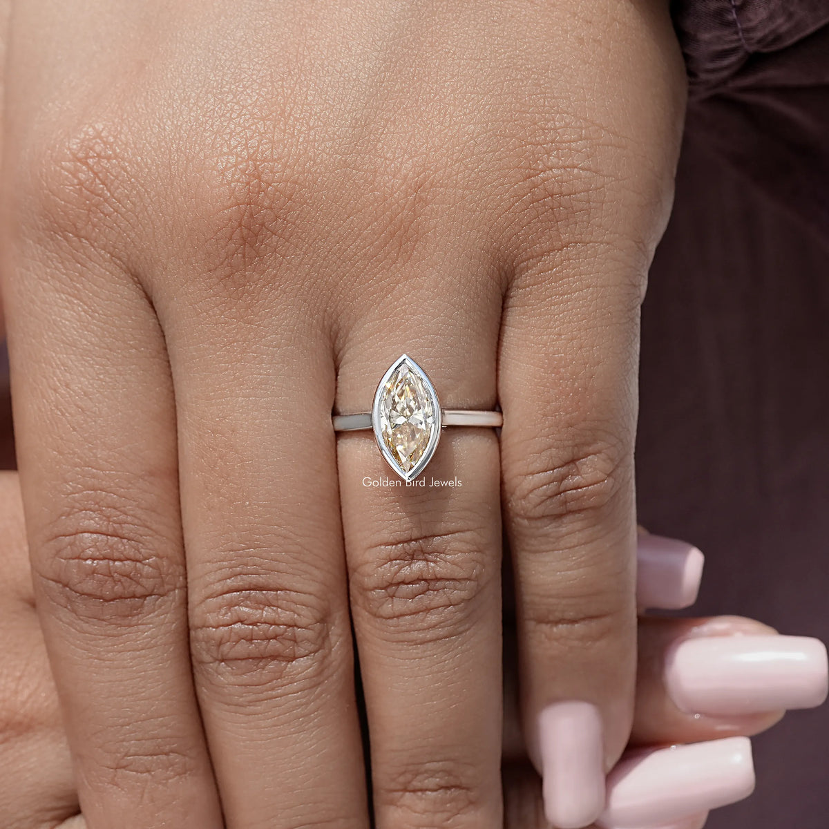 Silver marquise bezel engagement ring with faceted marquise-cut center stone on hand