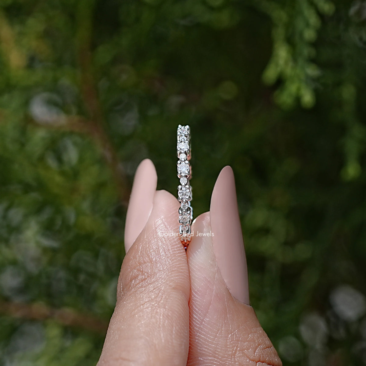 Silver eternity band side view with round moissanite stones in a vertical row