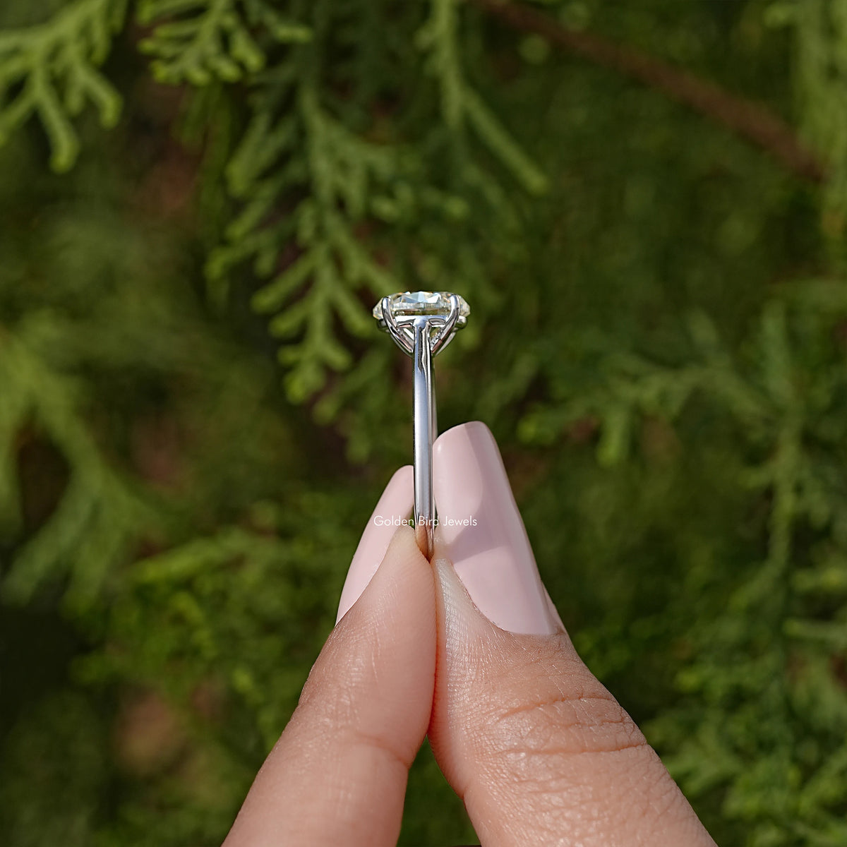 Silver oval moissanite solitaire ring, side view of prong setting and oval stone