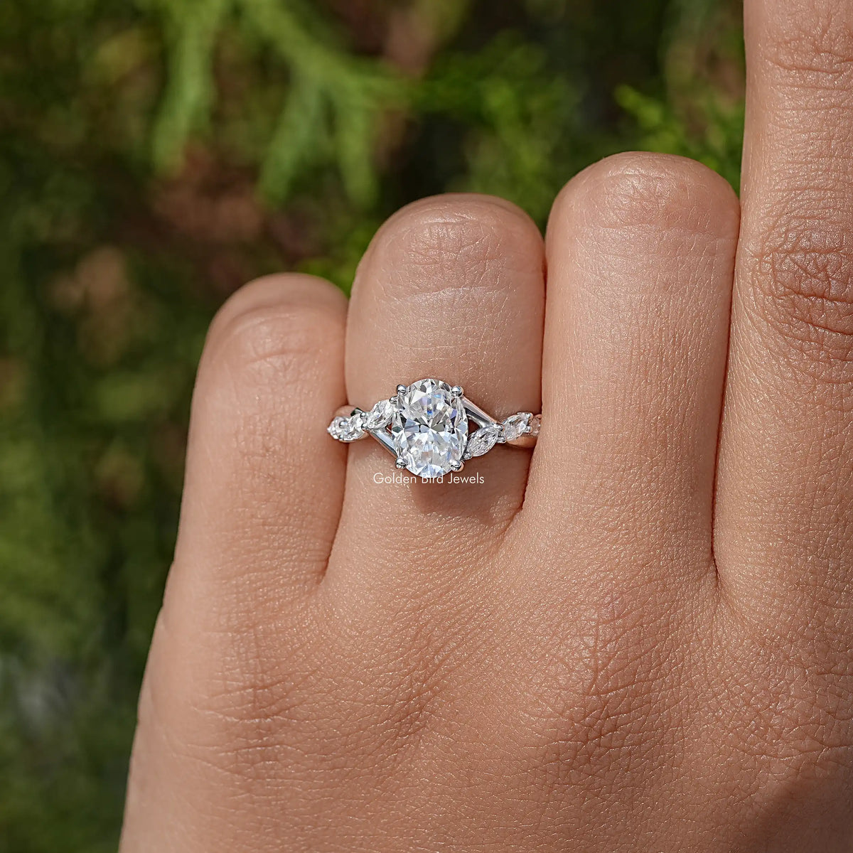Oval moissanite solitaire ring on finger, floral side stones, sterling silver band