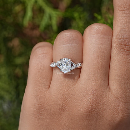 Oval moissanite solitaire ring on finger, floral side stones, sterling silver band