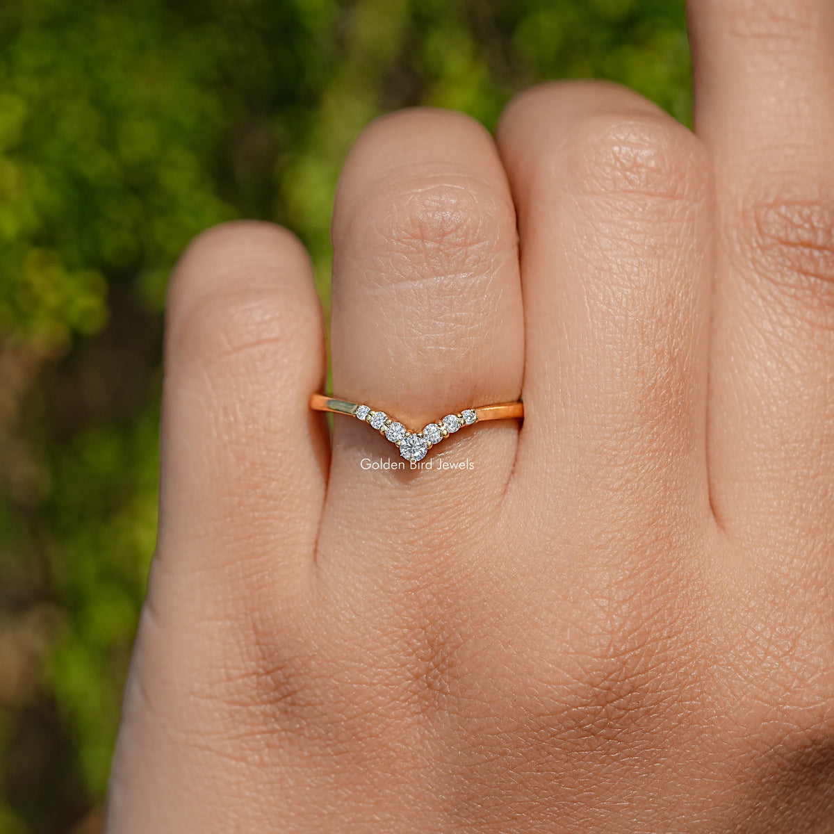 Yellow gold chevron V moissanite ring on hand, slim band with central V detail