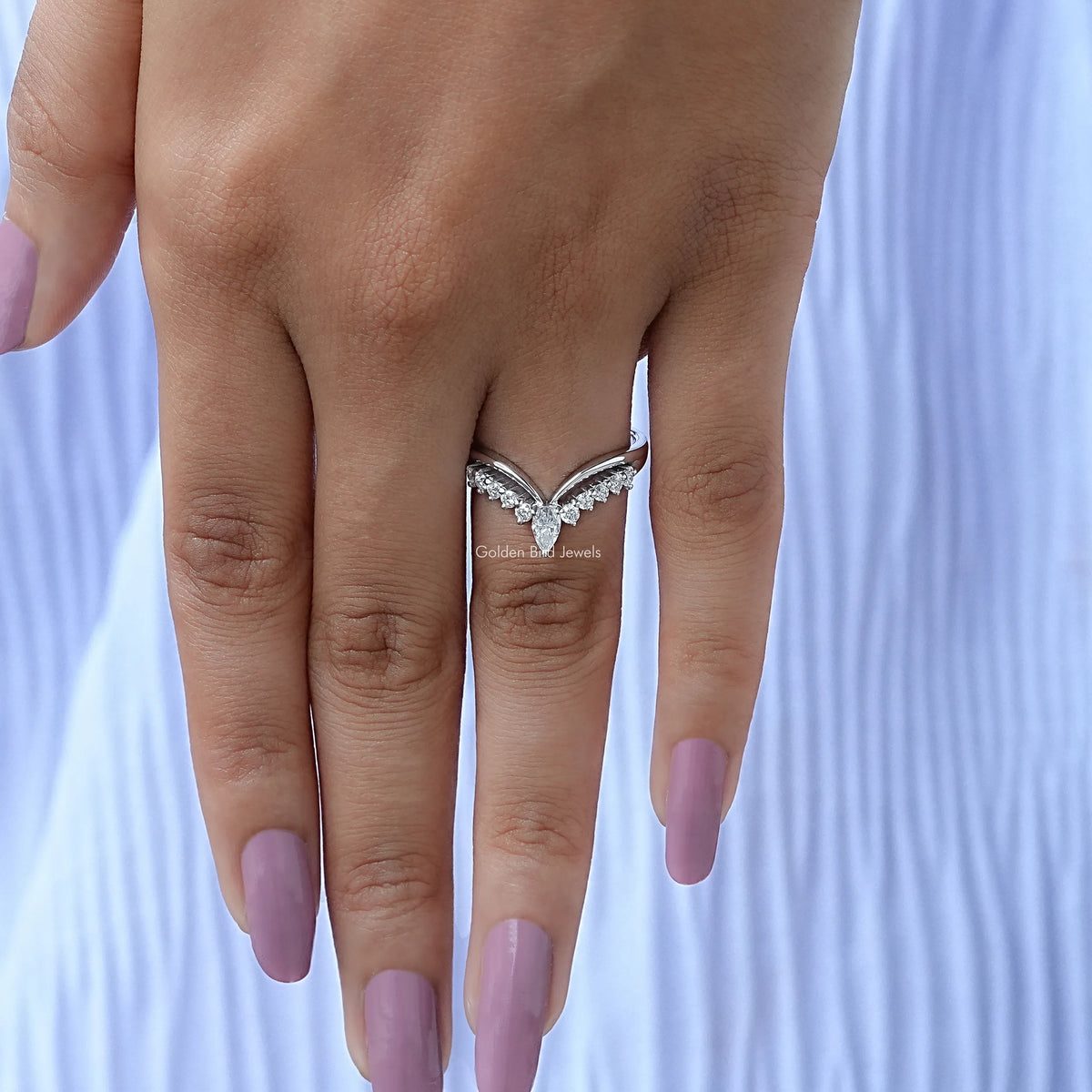 Silver pear-cut chevron wedding band with sparkling clear stones on finger