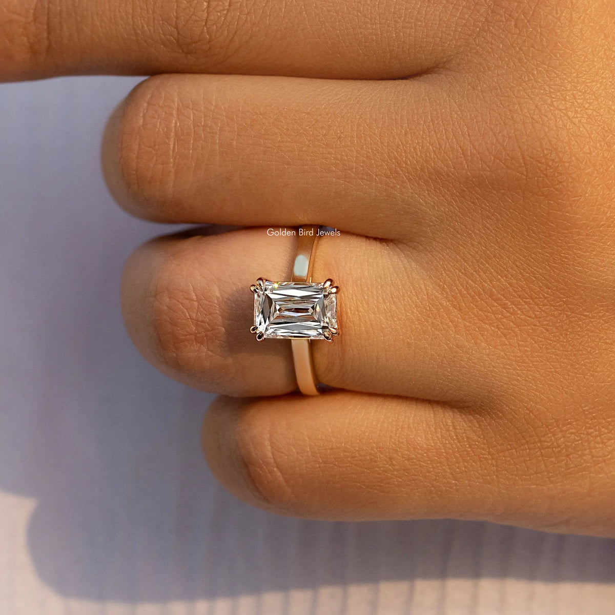 Moissanite solitaire engagement ring with rectangular stone, gold-tone band side view