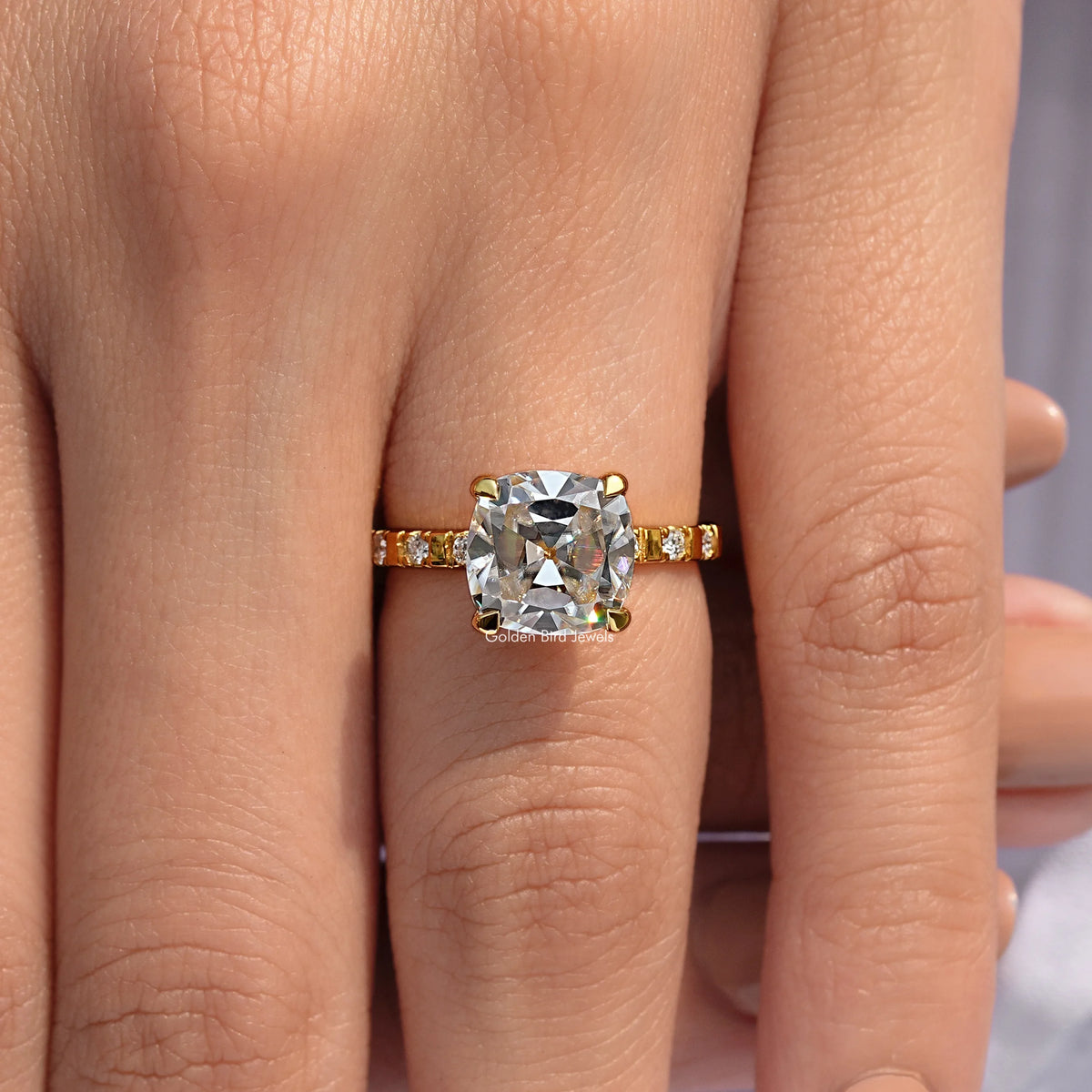 Gold-tone cushion-cut moissanite ring with small side stones on a slim band