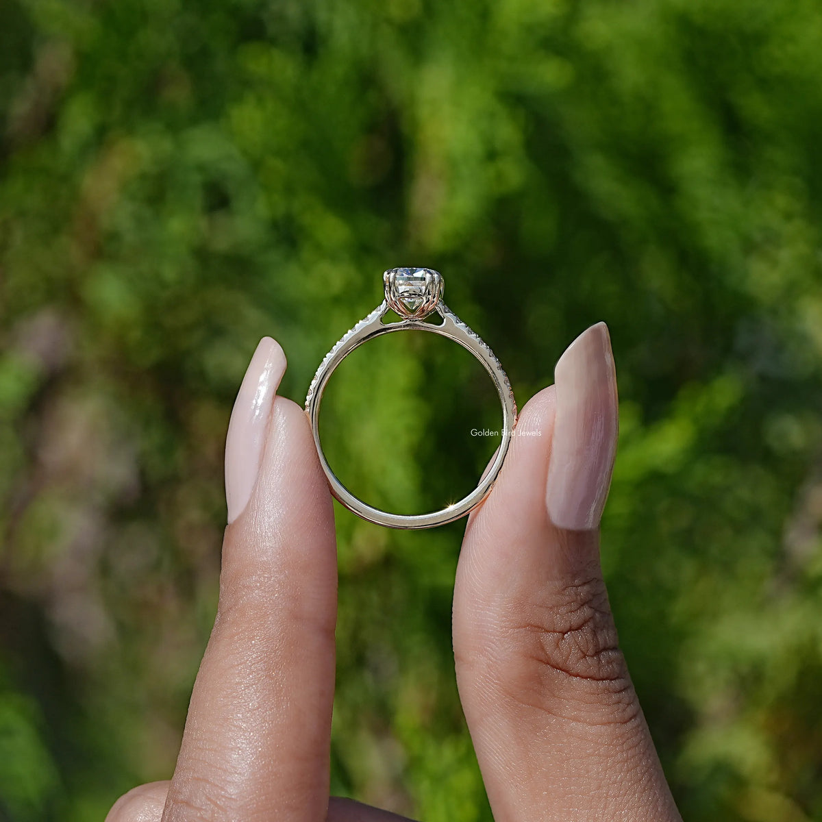 Elongated cushion moissanite ring held up, silver-tone setting with prongs