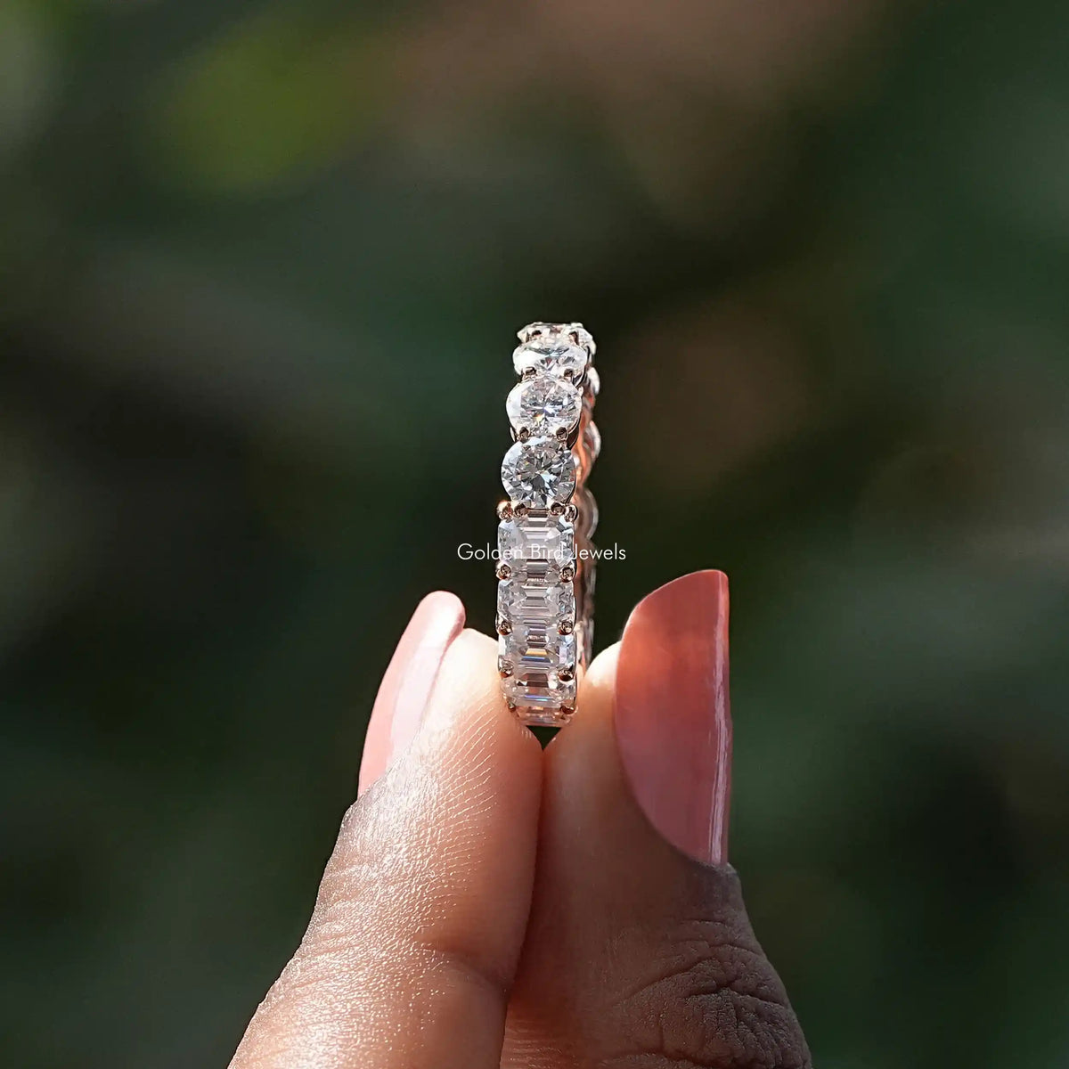 Moissanite round-stone ring band detail with prongs, close-up on fingers
