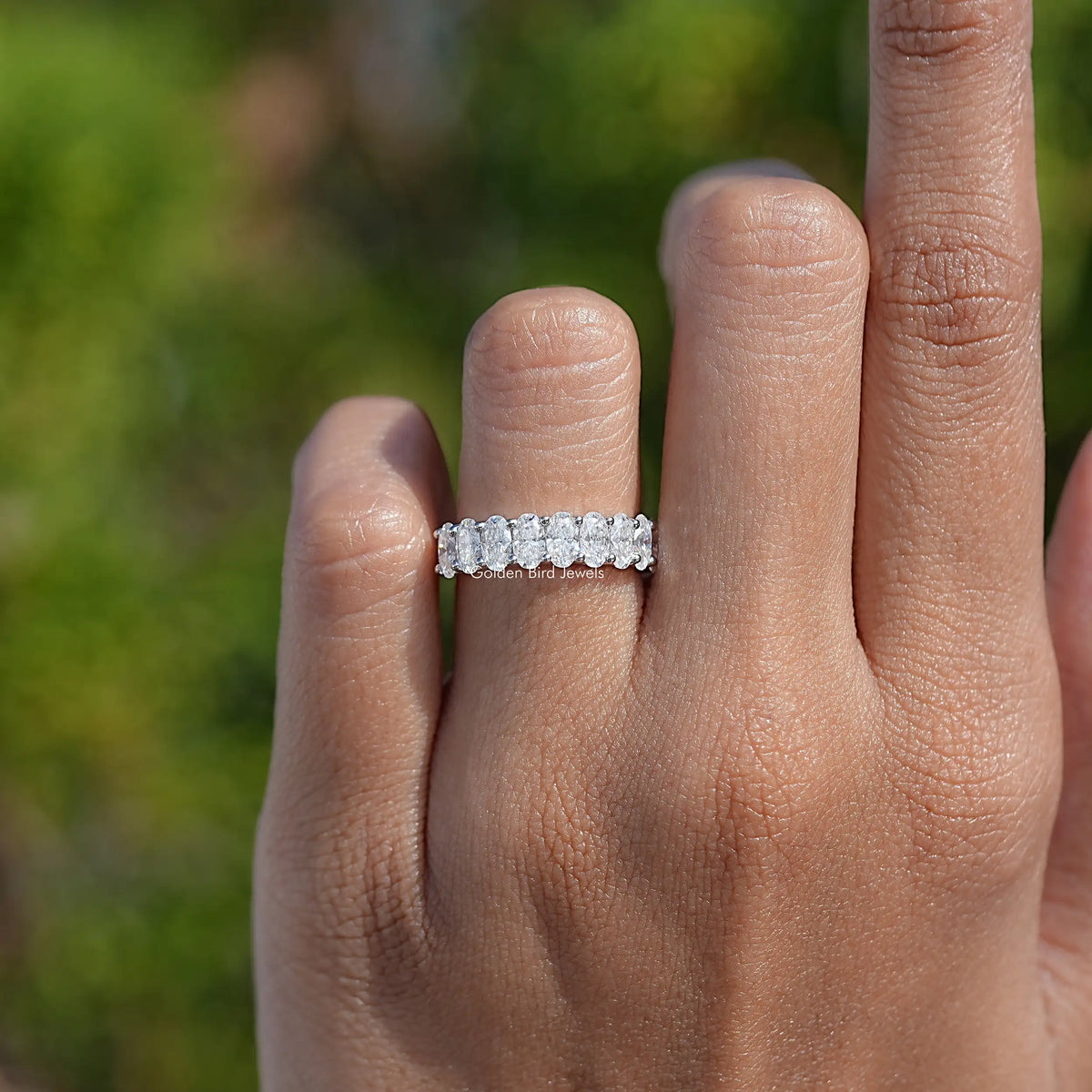 14K white gold half eternity ring with oval moissanite stones, on top of finger