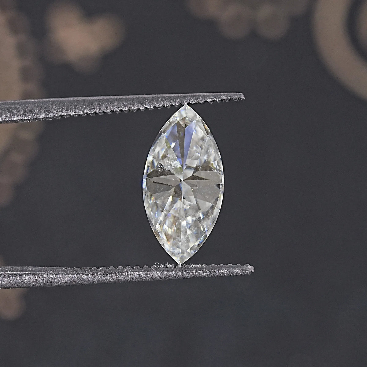 Marquise moissanite loose stone held in tweezers, clear faceted sparkle