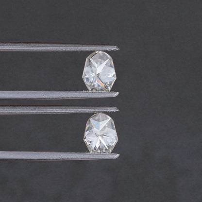 Two shield-cut moissanite stones shown in metal prongs, angled close view