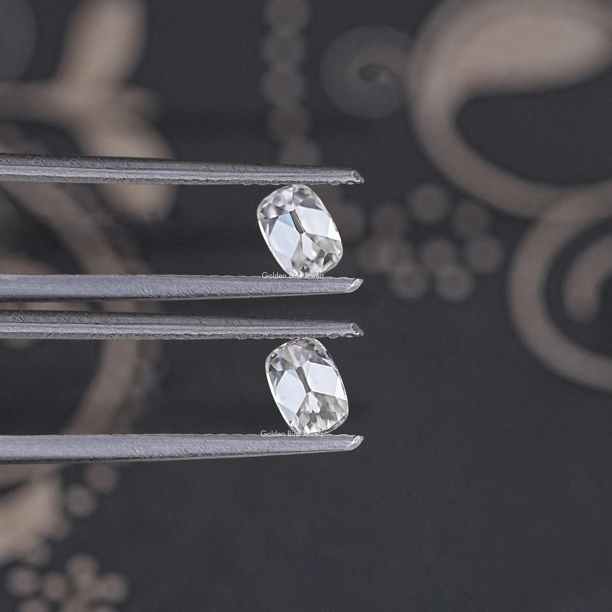 Pair of colorless old mine cushion moissanite stones on metal prongs