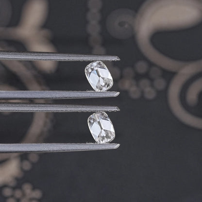 Pair of colorless old mine cushion moissanite stones on metal prongs