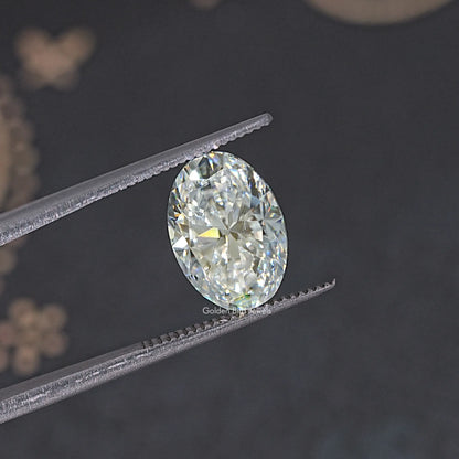 Oval-cut moissanite loose stone, faceted oval in metal tweezers