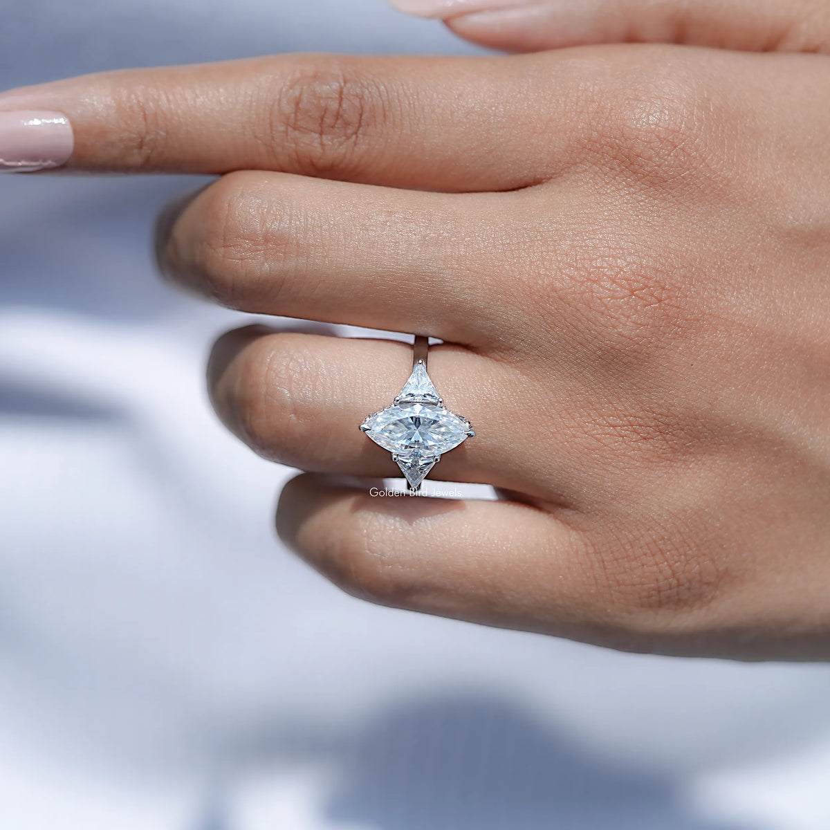 Three-stone moissanite ring close-up on hand, marquise center and triangle side stones.