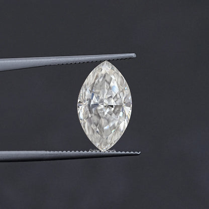 Marquise-cut moissanite stone in tweezers, faceted clear white sparkle
