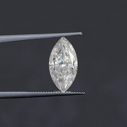 Marquise-cut moissanite loose stone held between metal tweezers, clear white