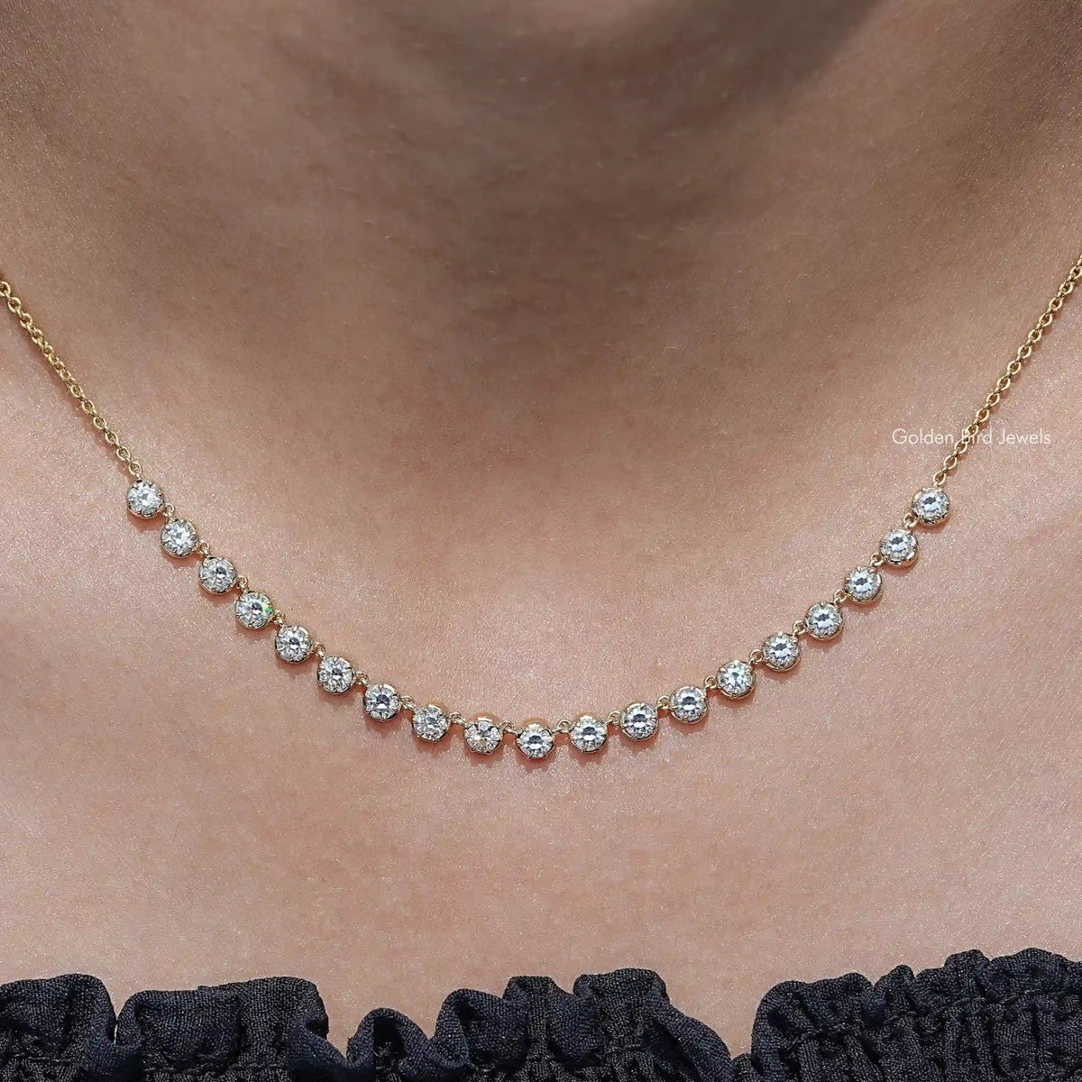 Gold-tone tennis necklace with small round-cut moissanite stones in a line
