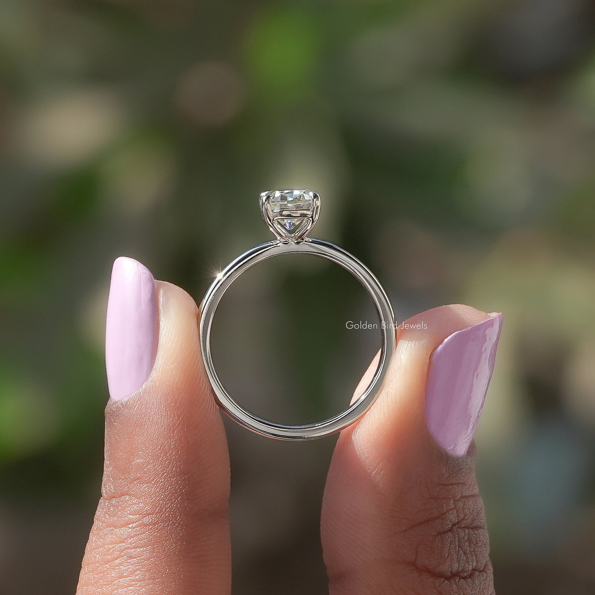 Silver moissanite solitaire ring viewed from side, cushion-cut center in prongs