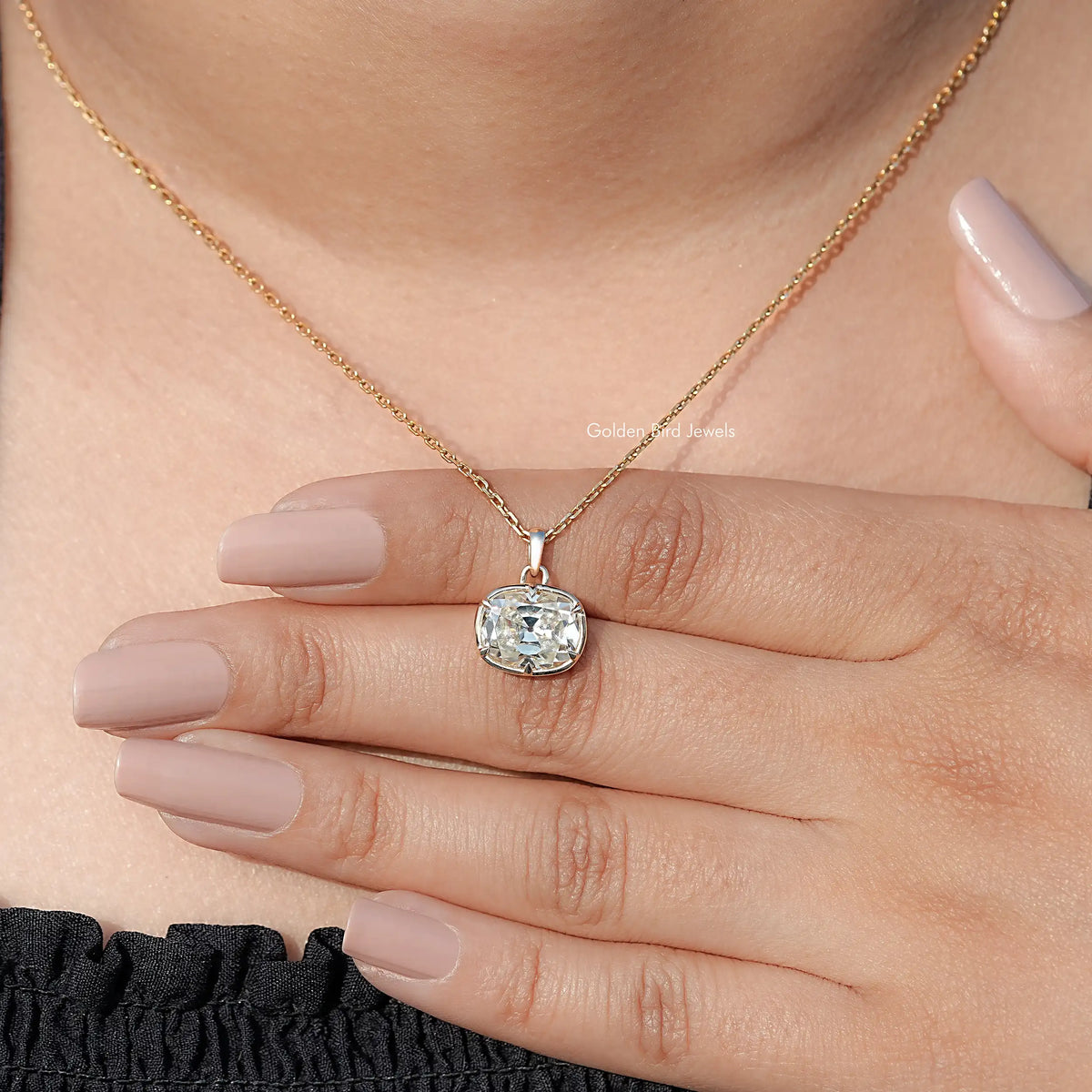 Cushion-cut moissanite solitaire pendant necklace on finger and hand, gold chain