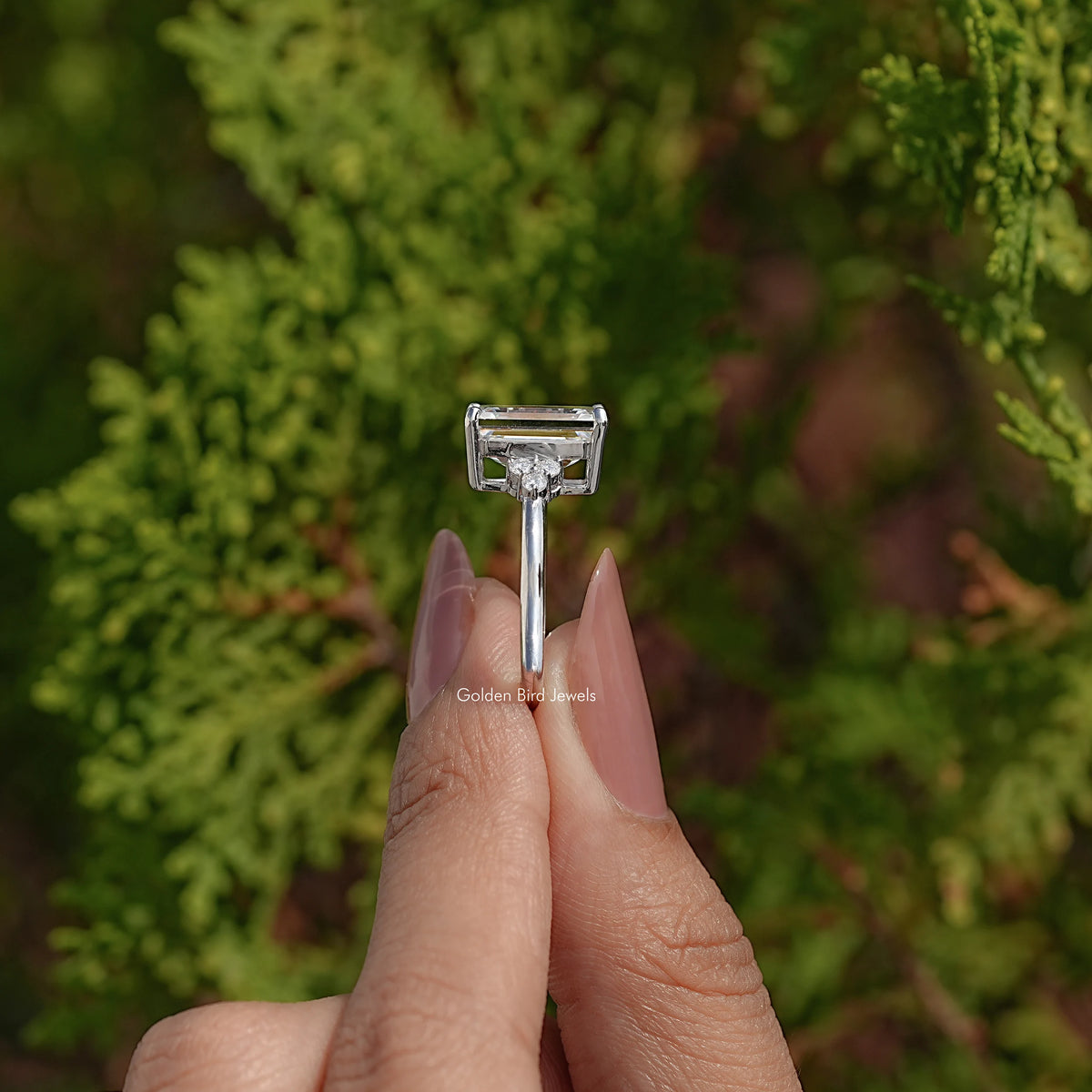 Side view of emerald-cut moissanite ring with prong-set rectangular center