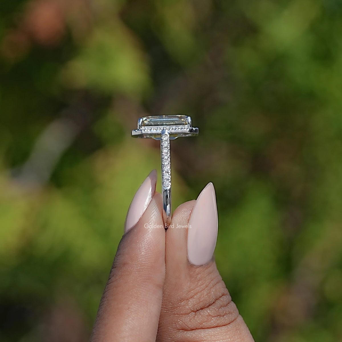 Emerald-cut halo moissanite ring in silver, shown in side profile with pavé band