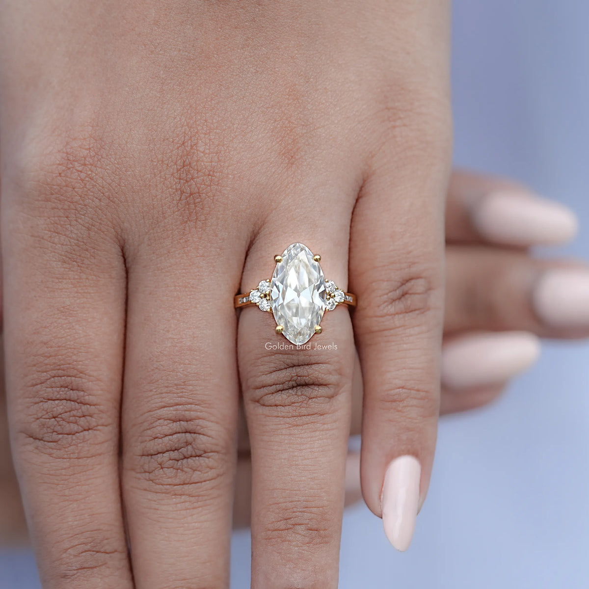 Oval moissanite engagement ring with round side stones, held on hand