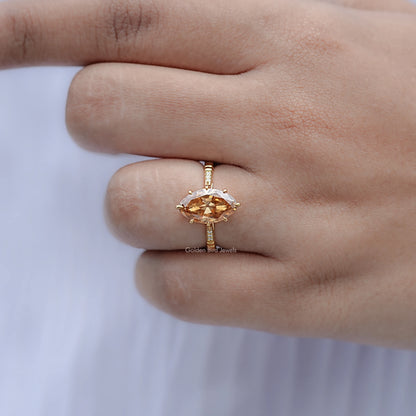 Gold-tone ring with oval amber center stone on thin band, finger close-up