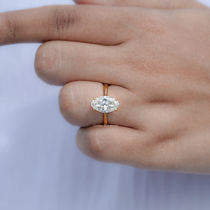 Gold band oval moissanite ring with hidden halo, close-up on fingers