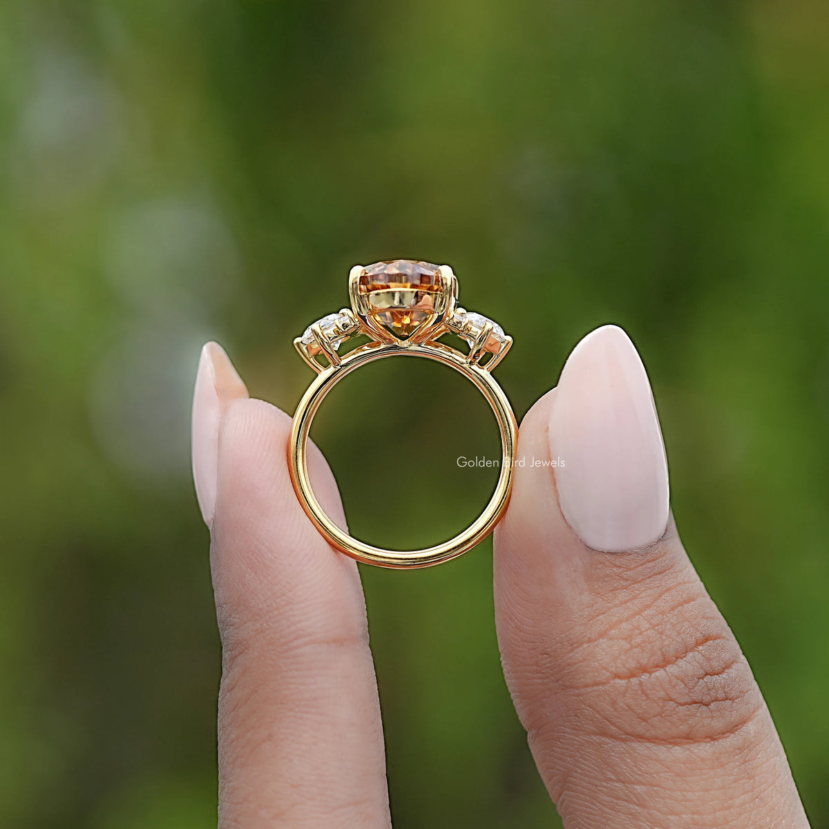 Moissanite engagement ring side view with oval top setting and prongs, gold tone