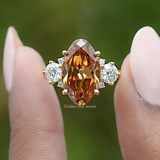 Moissanite engagement ring with large oval amber center, four round white side stones, gold