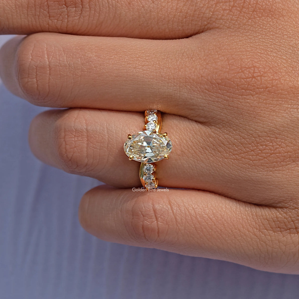 Gold-tone infinity ring featuring an oval old mine center stone and small round side stones