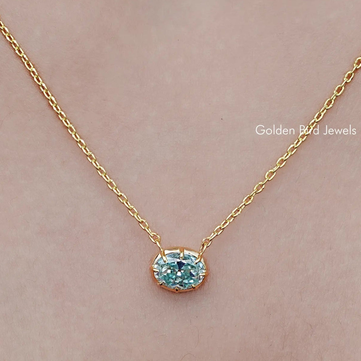Oval moissanite solitaire pendant necklace with gold-tone chain and blue gemstone