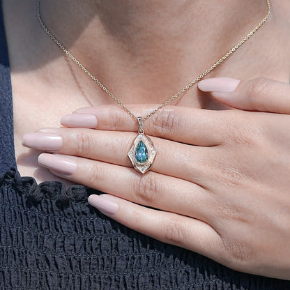 Pear-cut moissanite pendant necklace held in hands, teal center stone visible
