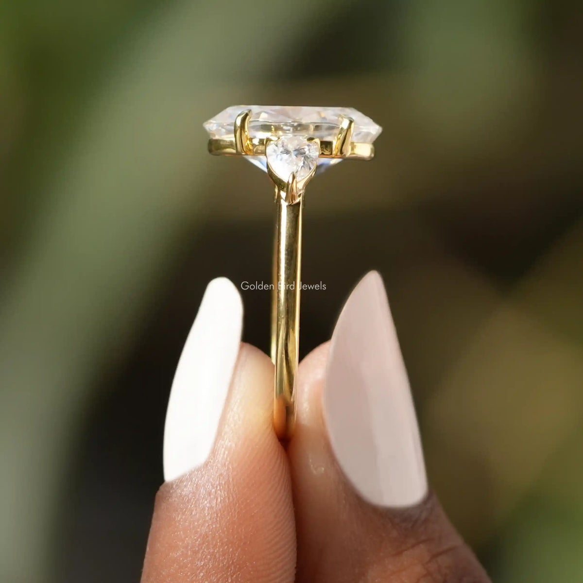 Side View of Oval And Pear Cut Moissanite Three Stone Ring In two fingers