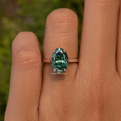925 sterling silver oval-cut moissanite engagement ring on hand, emerald green center