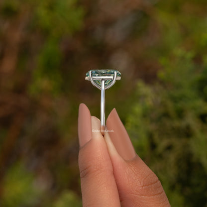 Sterling silver solitaire ring with oval teal moissanite viewed from the side.