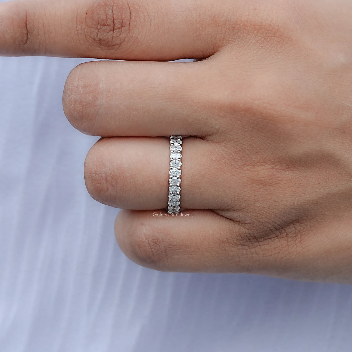 Sterling silver half-eternity ring with oval moissanite stones, narrow profile on finger