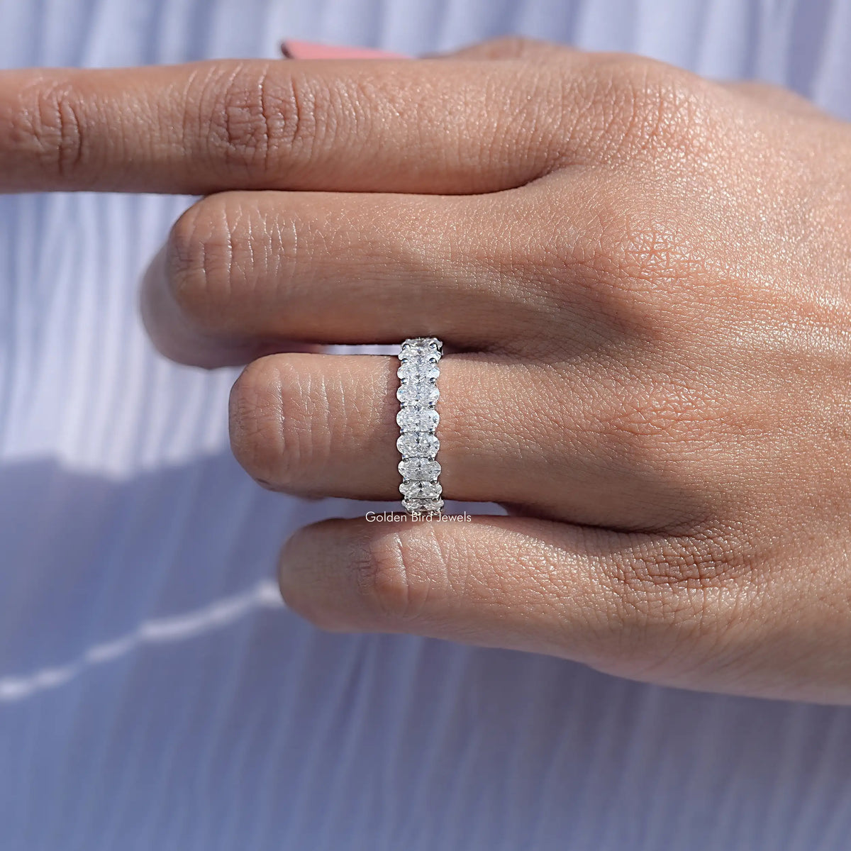 14K white gold half eternity band with oval moissanite stones, on hand