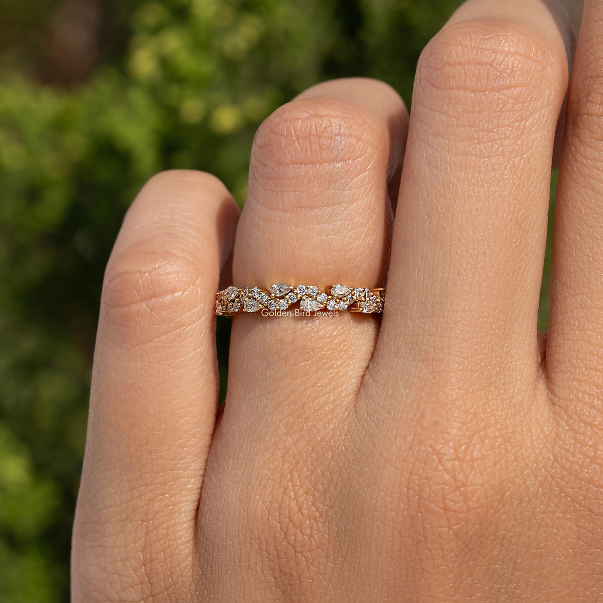 Moissanite eternity band on finger, round and pear stones in gold-tone row