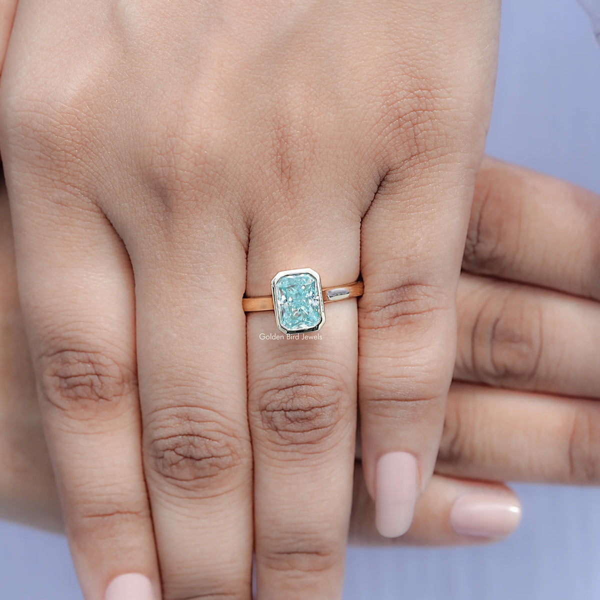 Blue moissanite bezel solitaire ring viewed from above on hand