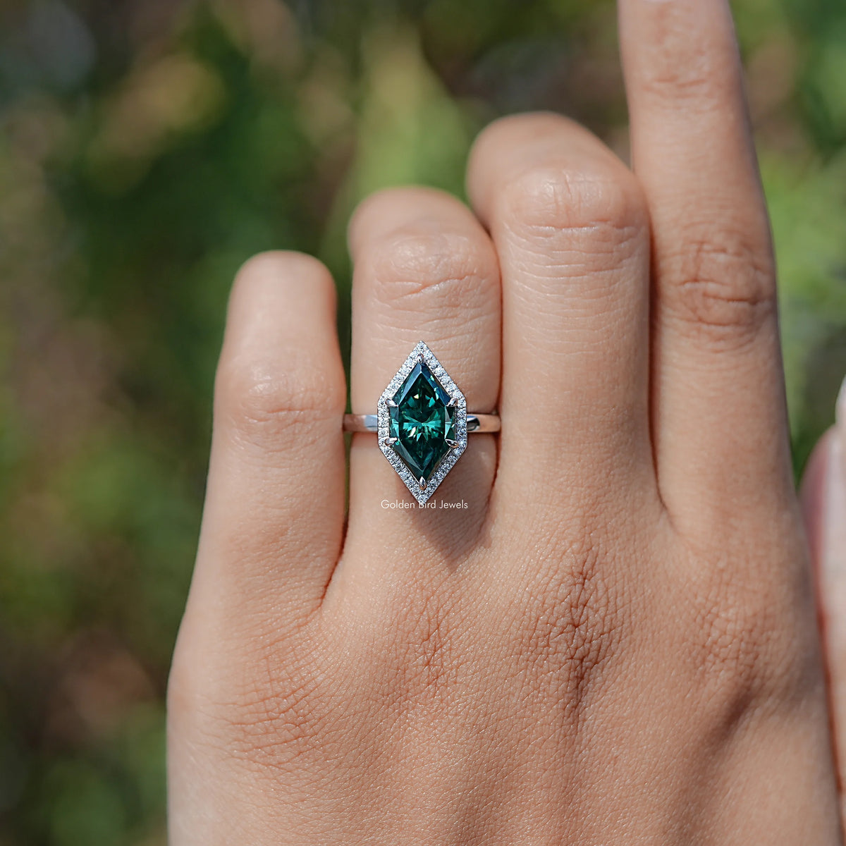 Teal marquise halo engagement ring with rectangular center stone, side view on hand