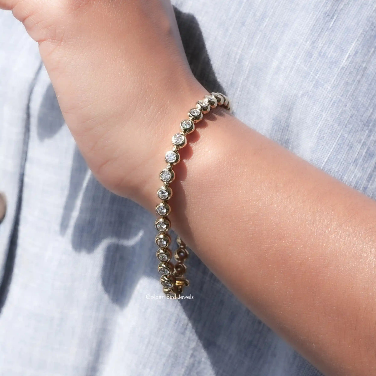 Moissanite bezel setting bracelet with round stones, worn on wrist close-up