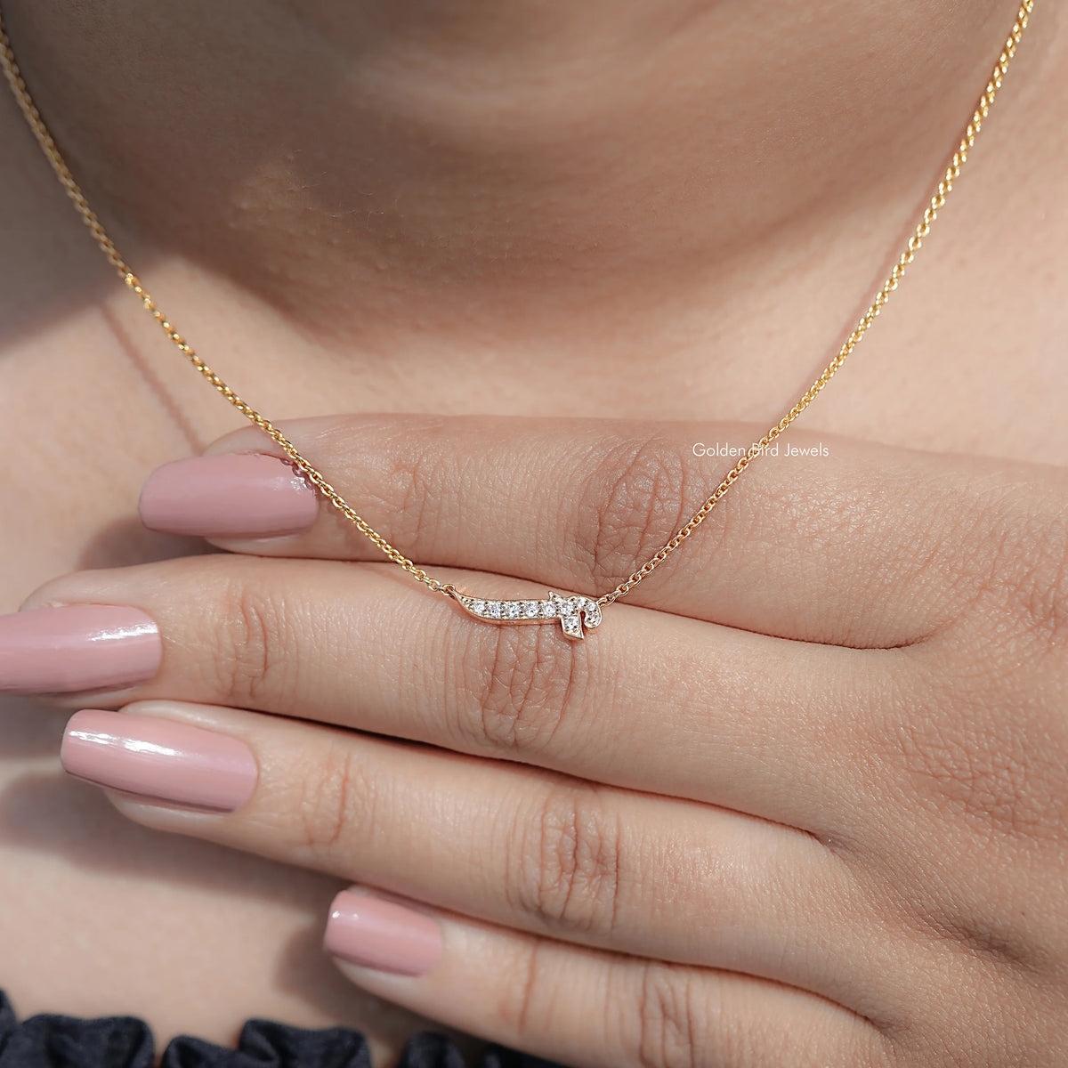 Gold-tone initial pendant necklace with round-cut stones, resting on fingers.