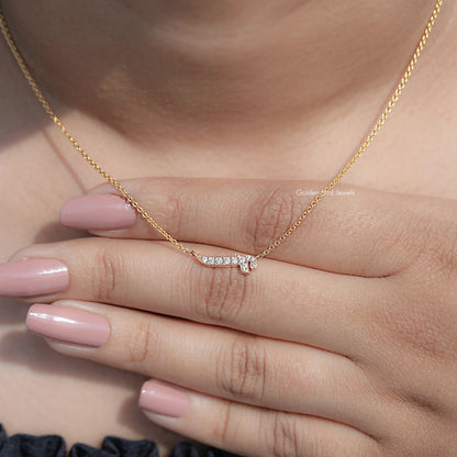 Gold-tone initial pendant necklace with round-cut stones, resting on fingers.