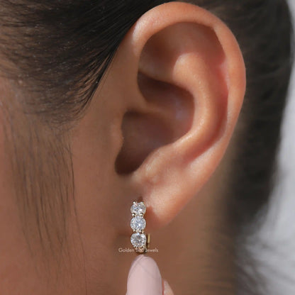 Silver-tone huggie hoop earrings with three round-cut sparkling stones on the ear