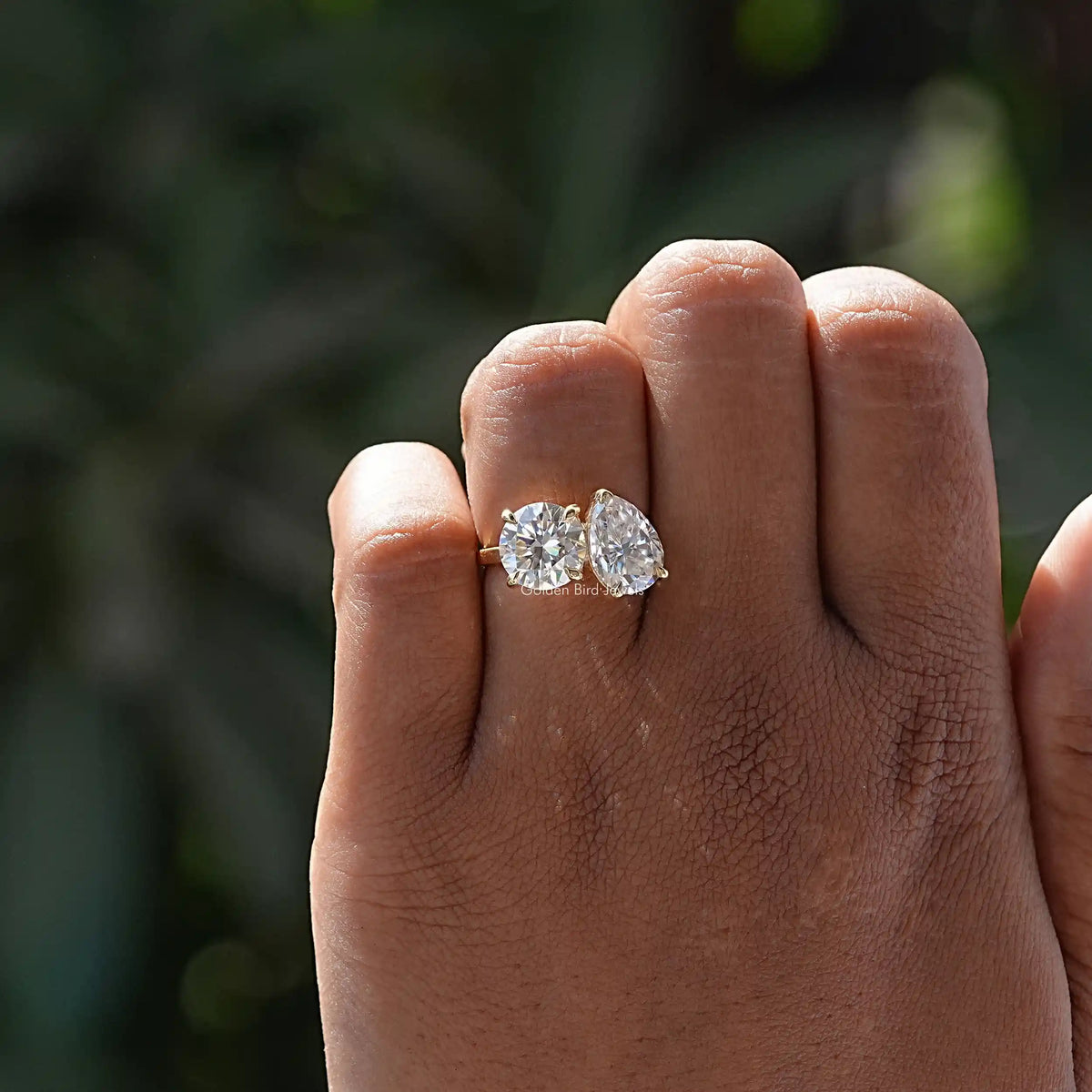 Moissanite toi et moi ring on hand with pear-cut and round stones