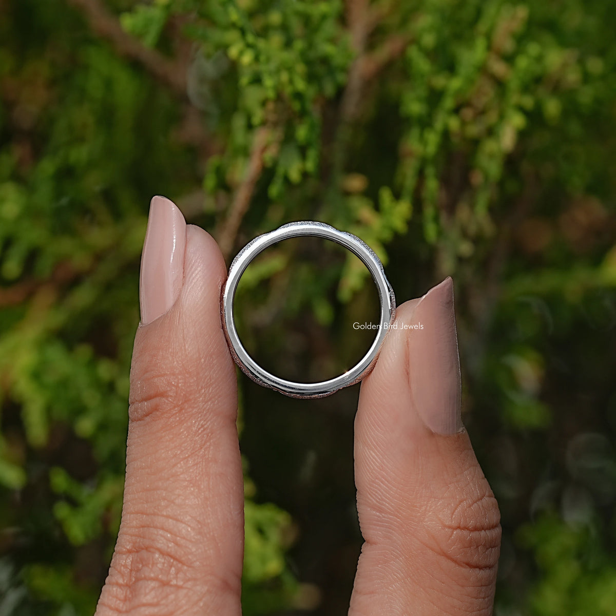 Round eternity band held between fingers, silver-tone metal, round stones around