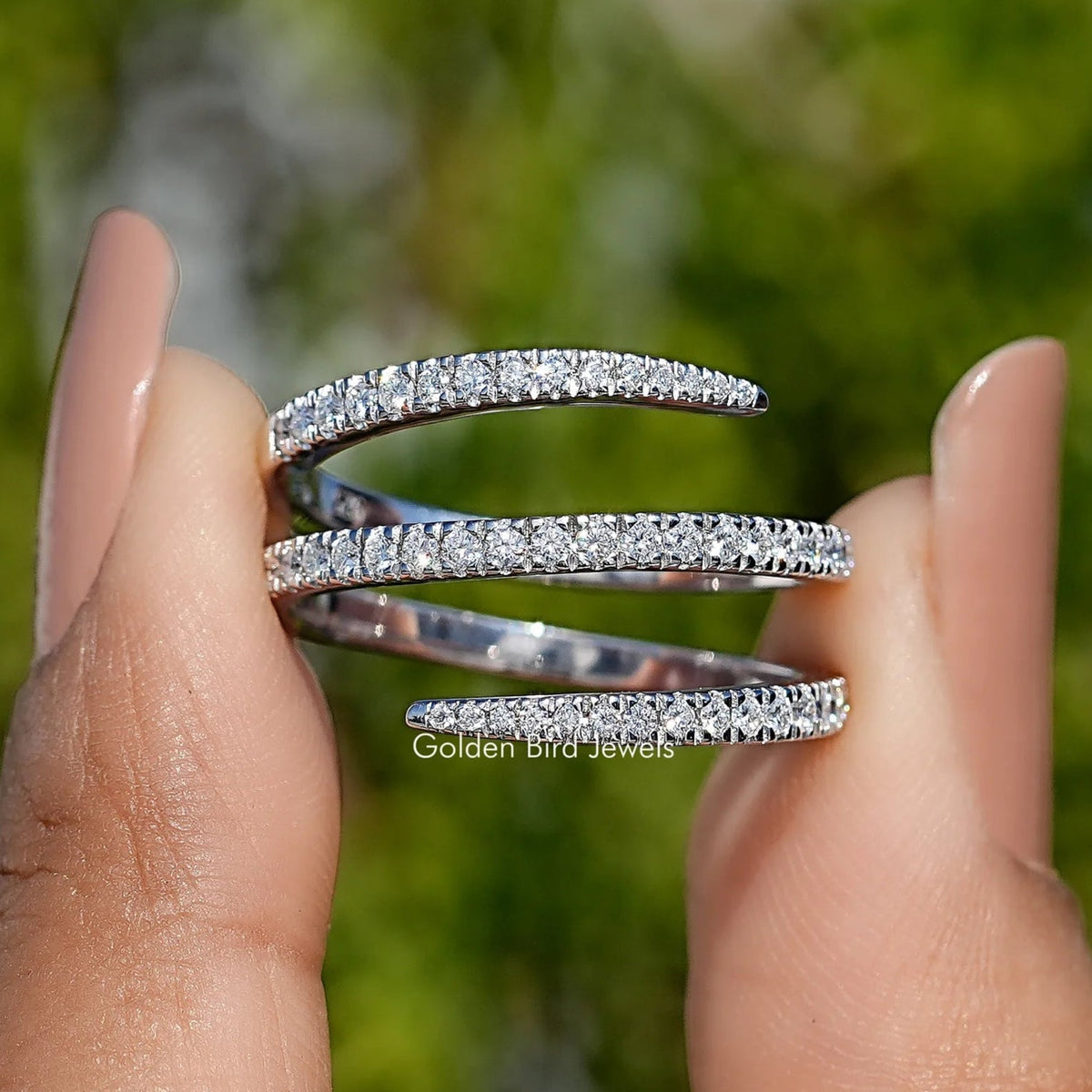 Silver moissanite spiral eternity band with round-cut stones, side view on fingers
